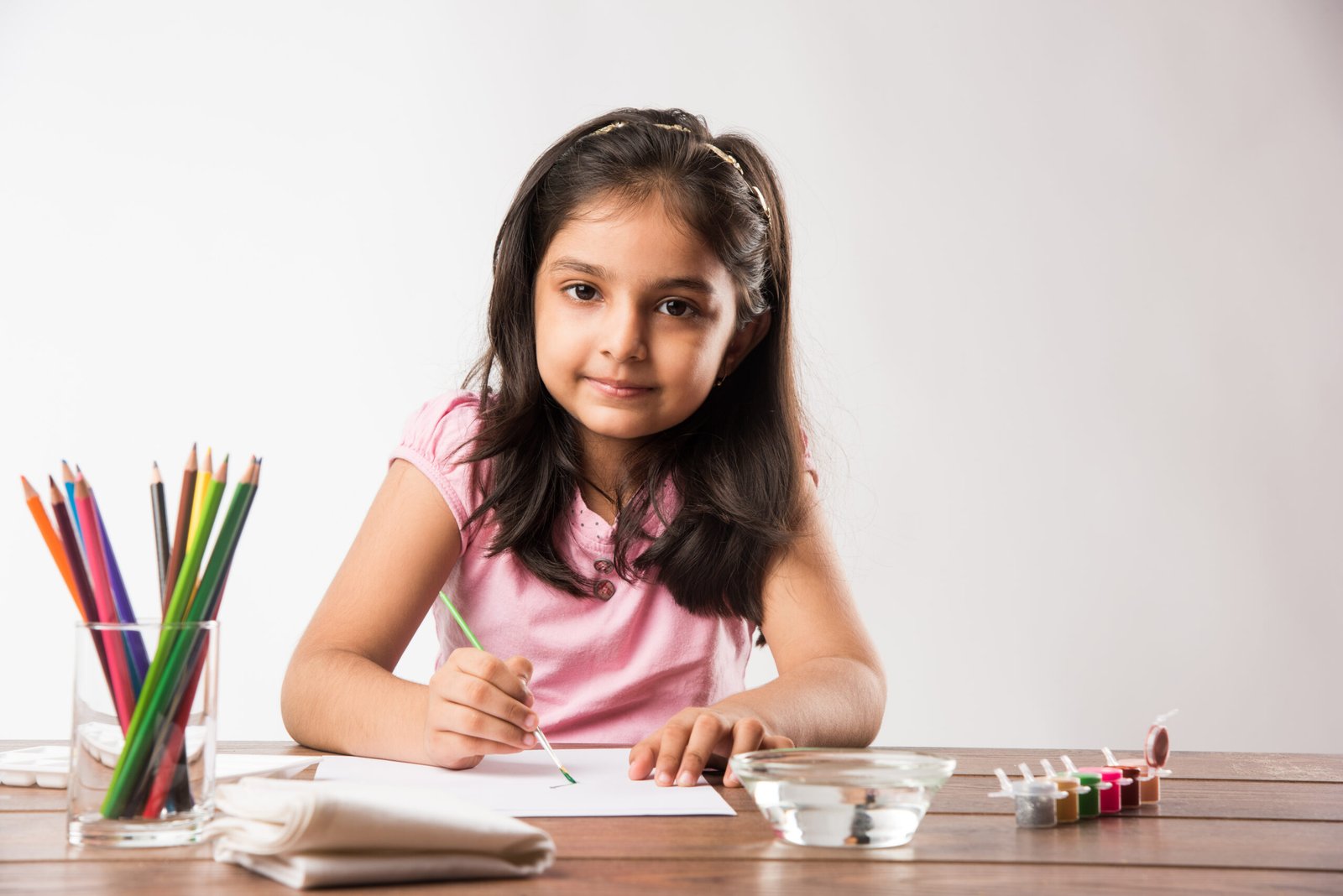 Cute little indian or asian girl colouring, drawing or painting with colours, pencils etc