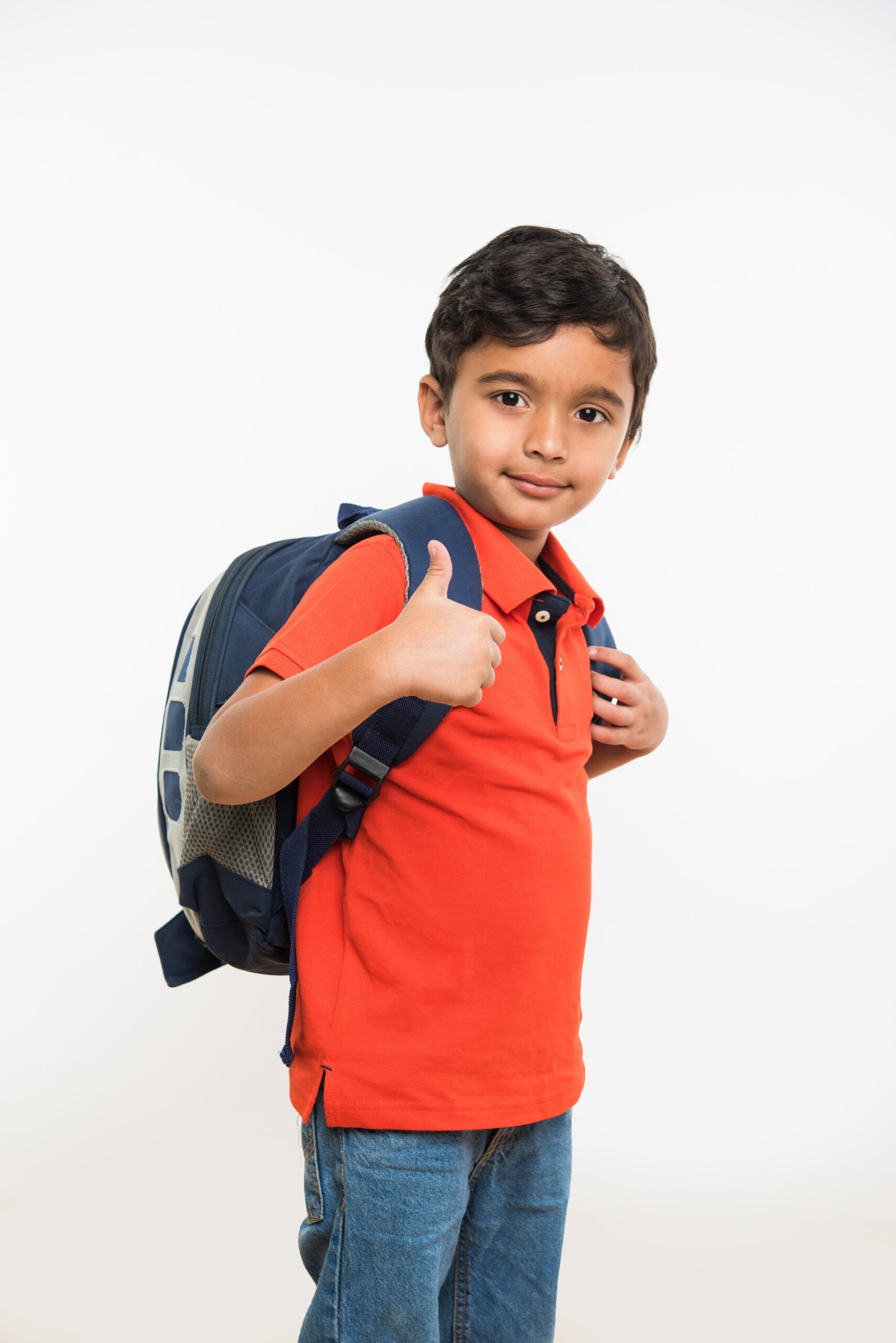 indian cute kid or boy leaving or going to school with small school bag, isolated over white background