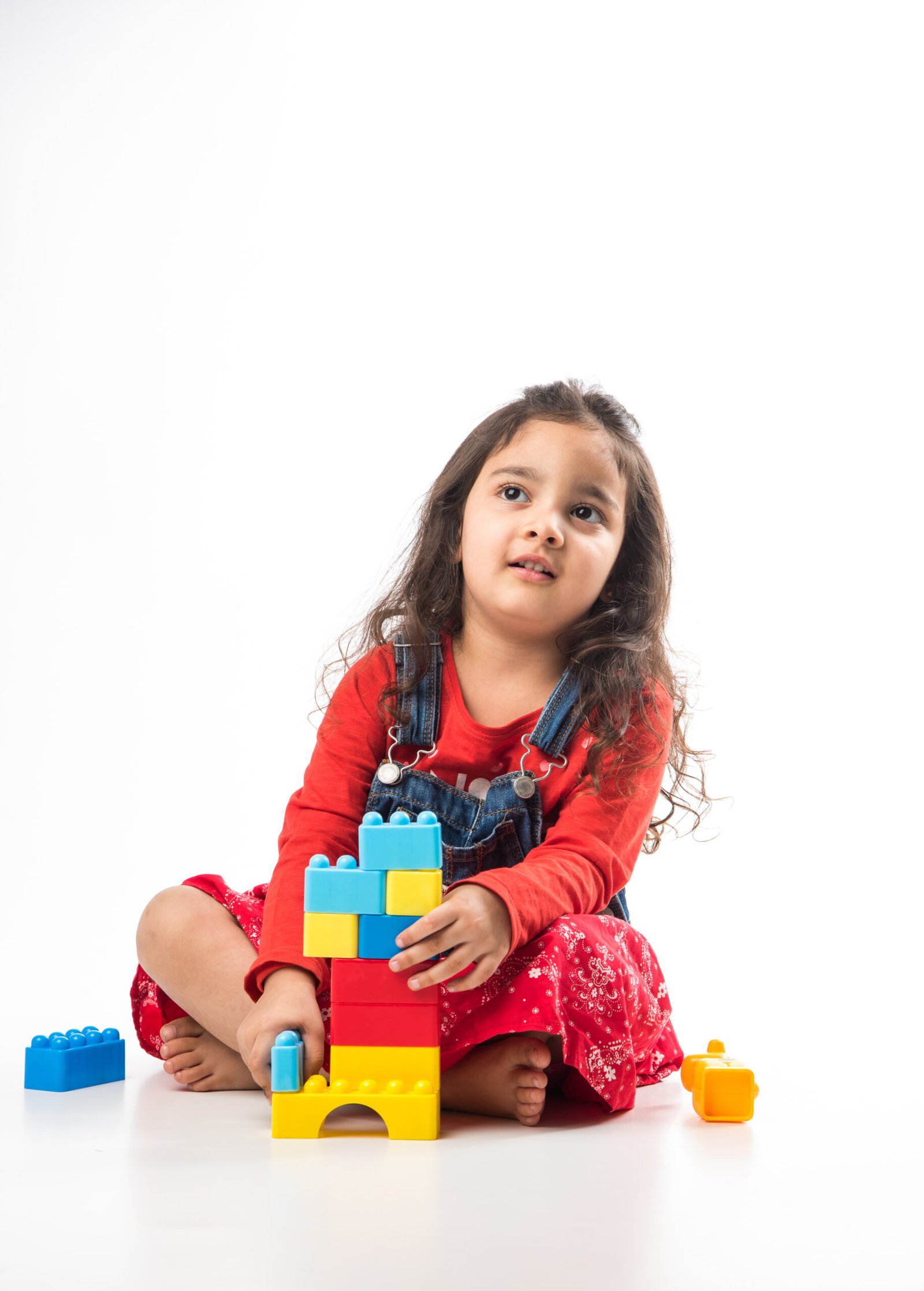 Cute Little Indian Asian girl playing with colourful block toys over white background