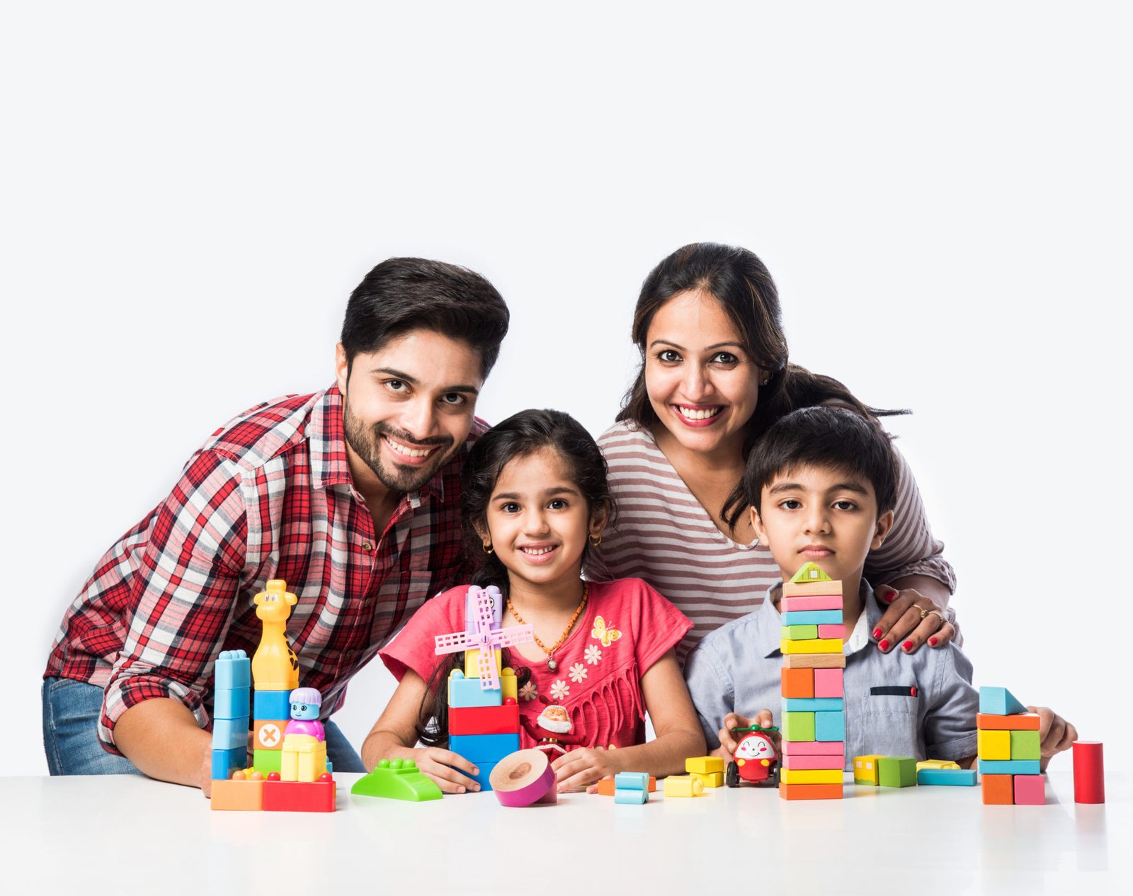 Indian small kids playing colourful block toys with young parents, against white background