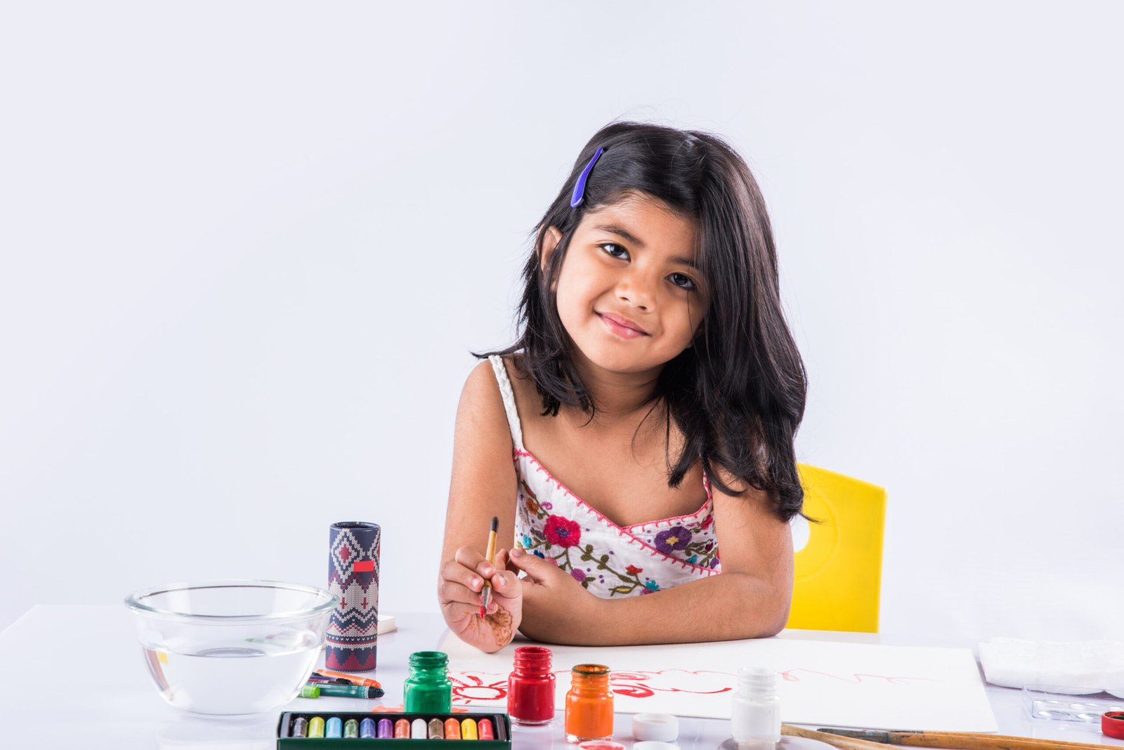 Cute little Indian or Asian Girl enjoying Painting at home with paper, water colour and art brush. Selective focus